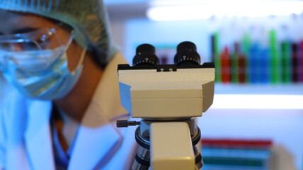 Scientists are doing research in a science lab. A medical chemist in a white coat, gloves and...