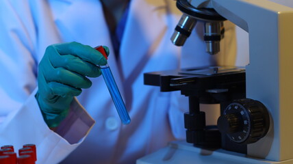 Scientists are doing research in a science lab. A medical chemist in a white coat, gloves and goggles looks at a glass tube. Compare two different liquid samples. and discuss future experiments.