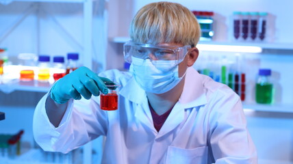 Scientists are doing research in a science lab. A medical chemist in a white coat, gloves and goggles looks at a glass tube. Compare two different liquid samples. and discuss future experiments.