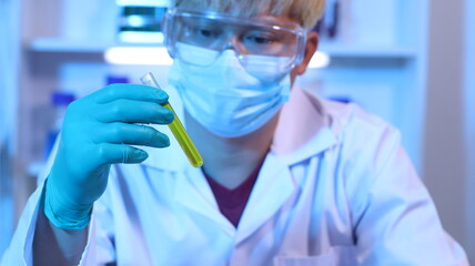 Scientists are doing research in a science lab. A medical chemist in a white coat, gloves and...