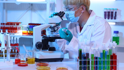 Scientists are doing research in a science lab. A medical chemist in a white coat, gloves and...
