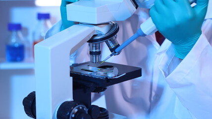 Scientists are doing research in a science lab. A medical chemist in a white coat, gloves and goggles looks at a glass tube. Compare two different liquid samples. and discuss future experiments.