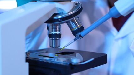 Scientists are doing research in a science lab. A medical chemist in a white coat, gloves and goggles looks at a glass tube. Compare two different liquid samples. and discuss future experiments.