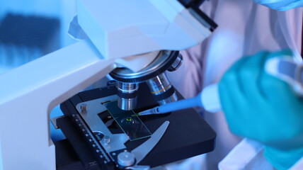 Scientists are doing research in a science lab. A medical chemist in a white coat, gloves and...