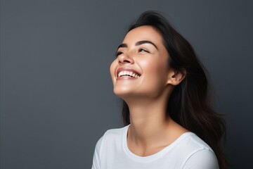 Portrait of a happy young woman laughing, over grey background.