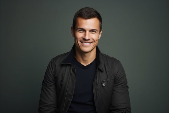 Portrait of a handsome young man in black leather jacket smiling at camera.