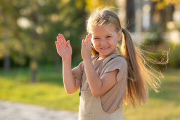 Charming happy little girl with long blonde hair have fun outdoor at sunset in the city park in summer. Summer vacation and family concept, Copy space