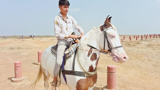 Boy riding a white horse on a dusty trail with clear skies in the background depicting rural adventure Boy loving horse