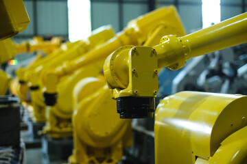 Row of yellow robot arms for automotive industry.Automated production line with robotic arms in factory.