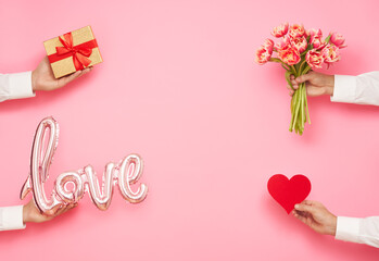 Man hands with balloon shape of love, bouquet of tulips, paper heart and gift box on pink background. International Women's Day, Valentine's day
