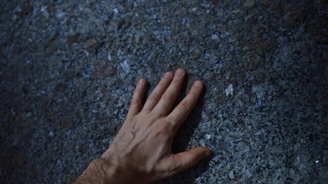 A man's hand touches a stone. Natural stone texture.