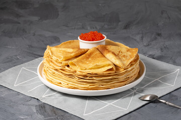 Pancakes with red caviar on grey background. Copy space