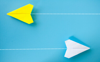 Top view of yellow and white paper airplane origami flying to a different direction on blue...