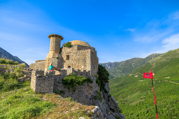 A tourist from Albania stands on the ramparts of Borsh Castle, excited to be able to see the beach in the distance and hear the waves crashing against the shore. - 738669599