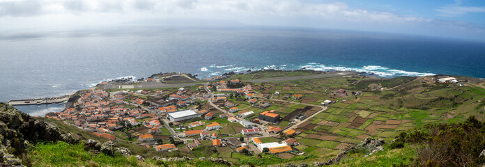 Vila do Corvo seen from above with Flores Island in the horizon below the clouds
