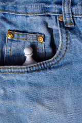 White chess in jeans pocket. Abstract background. Draped background of classic jeans fabric, texture. Close up