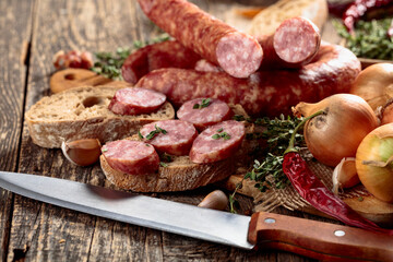 Dry-cured sausage with bread and spices on a old wooden table.