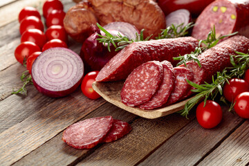 Food tray with delicious salami, ham, fresh sausages, tomato, and rosemary.