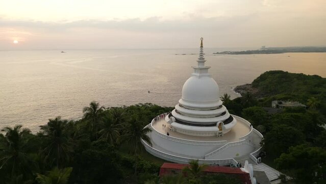 White pagoda buddhist temple among the jungle. Japanese Peace Pagoda in Sri Lanka aerial view.