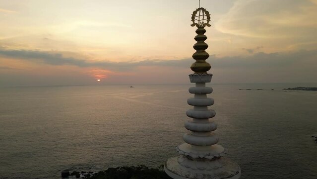 White pagoda buddhist temple top among the jungle at sunset. Japanese Peace Pagoda spire in Sri Lanka aerial view.
