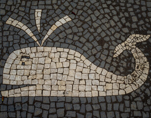 Black and white sidewalk stone pavement with a representation of a whale