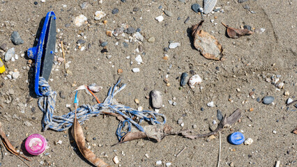 Top down view of assorted plastic rubbish and junk washed ashore onto sandy beach from ocean on a tropical island destination © Travelanza