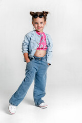 Full length portrait little child girl with hairstyle buns and glitter in pink t-shirt and jeans