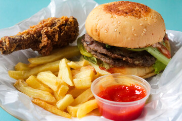 fast food such as hamburger, french fries, and fried chicken on the table