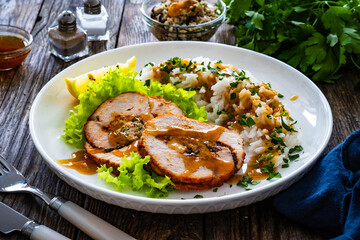 Stuffed turkey breast roulade with dried apricots and cranberries and boiled white rice on wooden table
