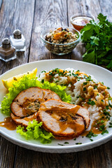 Stuffed turkey breast roulade with dried apricots and cranberries and boiled white rice on wooden table
