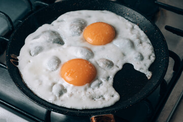 Frying egg in a cooking pan in the domestic kitchen.
