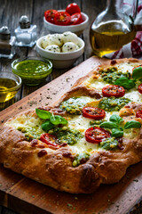 Pinsa Romana with mozzarella cheese and basil pesto on wooden table
