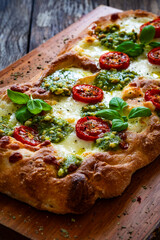 Pinsa Romana with mozzarella cheese and basil pesto on wooden table
