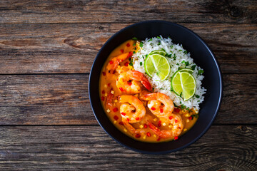 Fried shrimps with rice in mango sauce on wooden table
