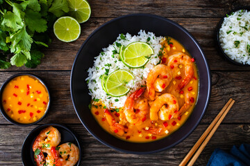 Fried shrimps with rice in mango sauce on wooden table
