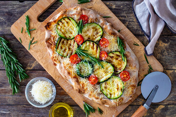Pinsa Romana with mozzarella cheese and grilled zucchini and rosemary on wooden table