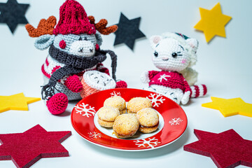 Various homemade cookies from the Christmas bakery on a small plate. And a moose and a cat amigurumi figures with Christmas clothes.