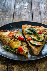 Pinsa Romana with mozzarella cheese and grilled zucchini and rosemary on wooden table