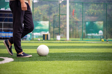 learning to play football. classic black and white soccer ball and football player's feet on the green grass of the field. Football match, training, hobby concept. teenage child kicks a ball.