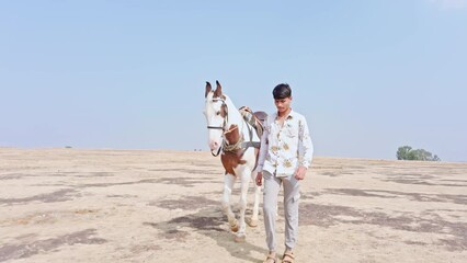 A man leading a horse on a desert dusty trail walking with a clear sky in the background