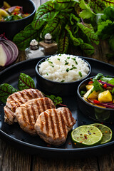 Fototapeta na wymiar Grilled pork loin steaks with boiled white rice and mango salad on wooden table 