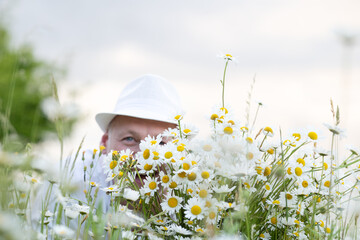 mature man with a large bouquet of daisies sat down in a meadow