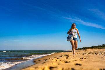 Beautiful mid adult woman walking on sunny beach
