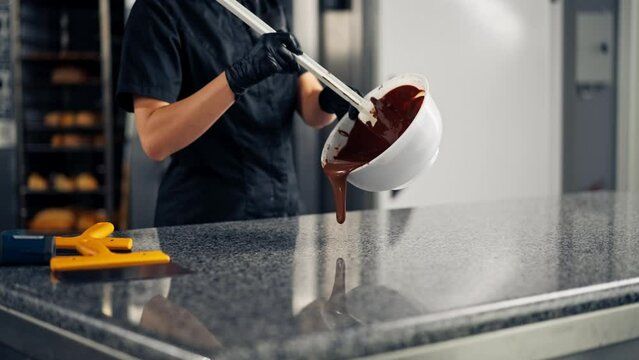 Girl chocolatier using a silicone spatula mixes chocolate for making desserts in pastry shop