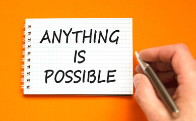 Anything is possible symbol. Concept words Anything is possible on beautiful white note. Beautiful orange background. Businessman hand. Business anything possible concept. Copy space.