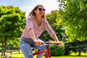 Obraz premium Beautiful mid adult woman riding bicycle in city park 