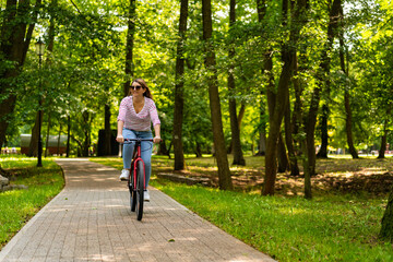 Fototapeta premium Beautiful mid adult woman riding bicycle in city park 