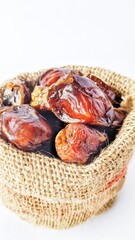Dried dates are in a burlap sack for breaking the fast in the holy month of Ramadan, on a white background