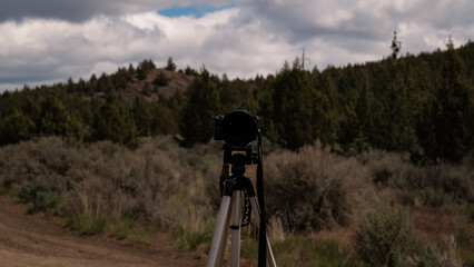 Naklejka premium camera on tripod in high desert brush landscape