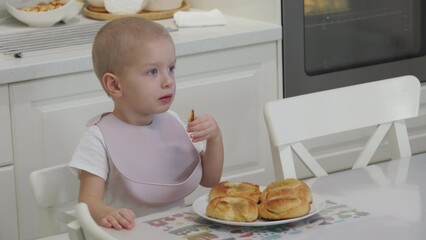 child little boy eating freshly baked homemade buns with apple jam